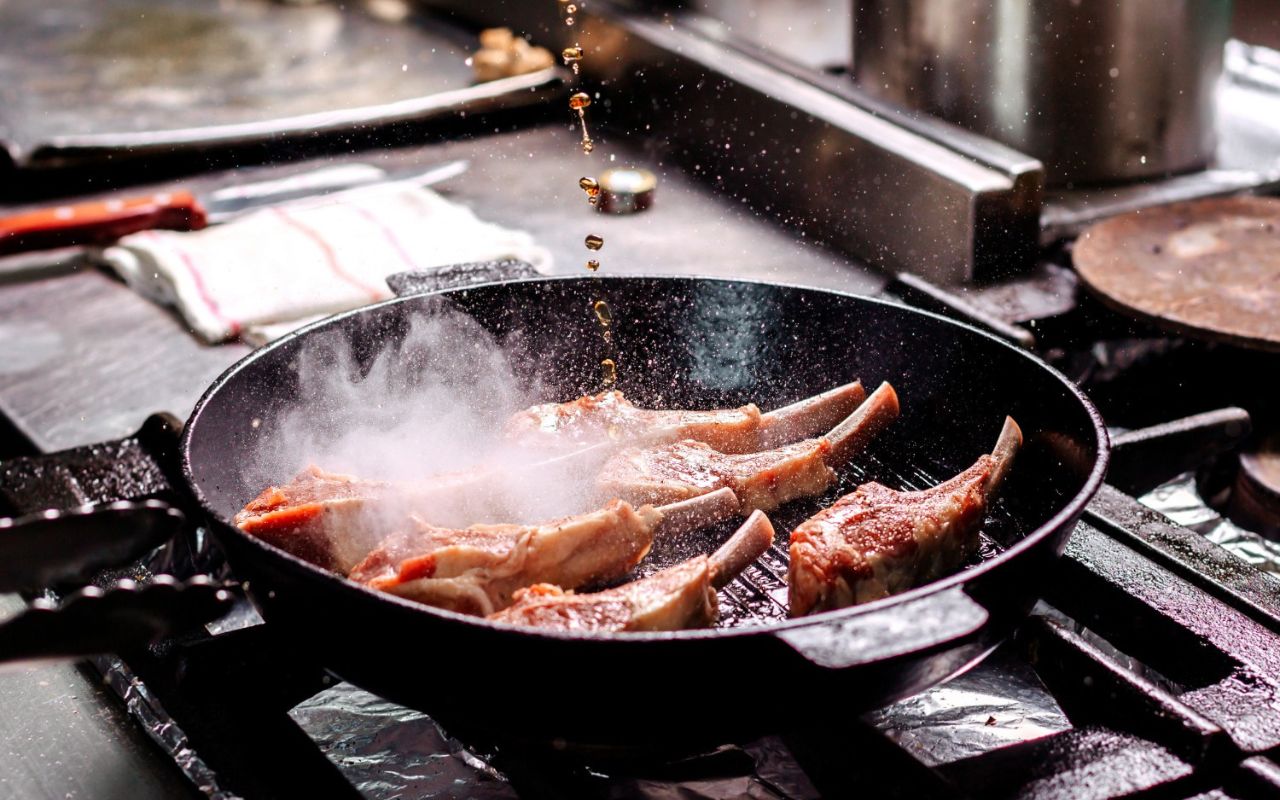 Pouring oil into a preheated pan before adding steak for searing