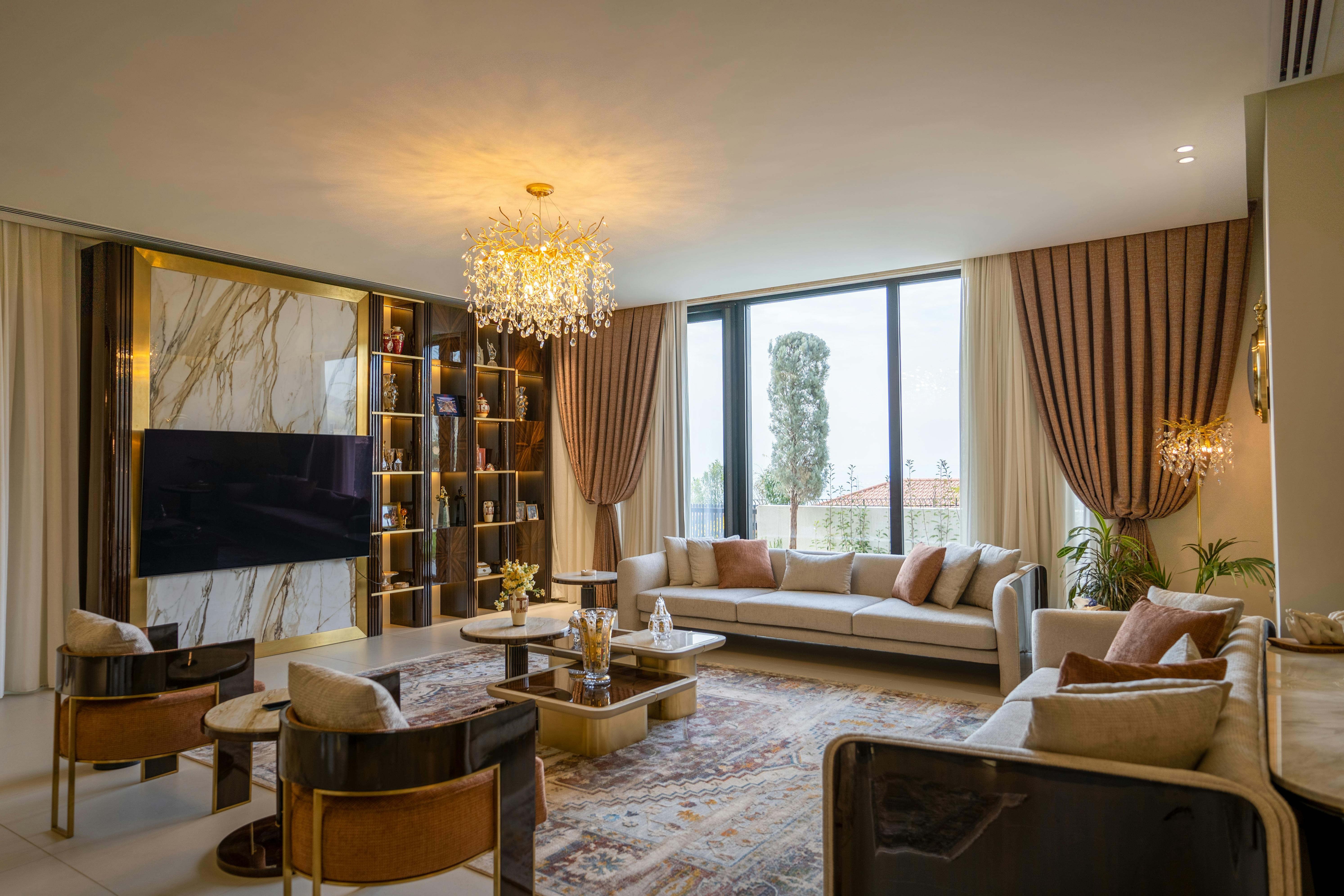 Modern Neo Deco living room with curved velvet sofa, brass chandelier, sunburst mirror, and geometric accents