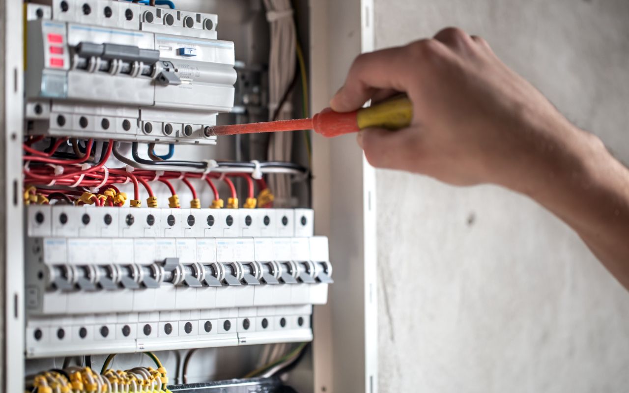 Tightening loose electrical wires inside a junction box to prevent fire hazards.
