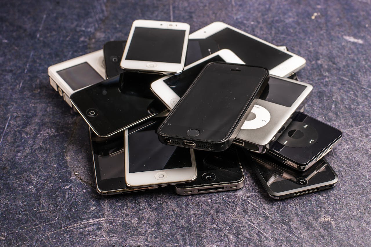 Stack of old smartphones/tablets on a desk.
