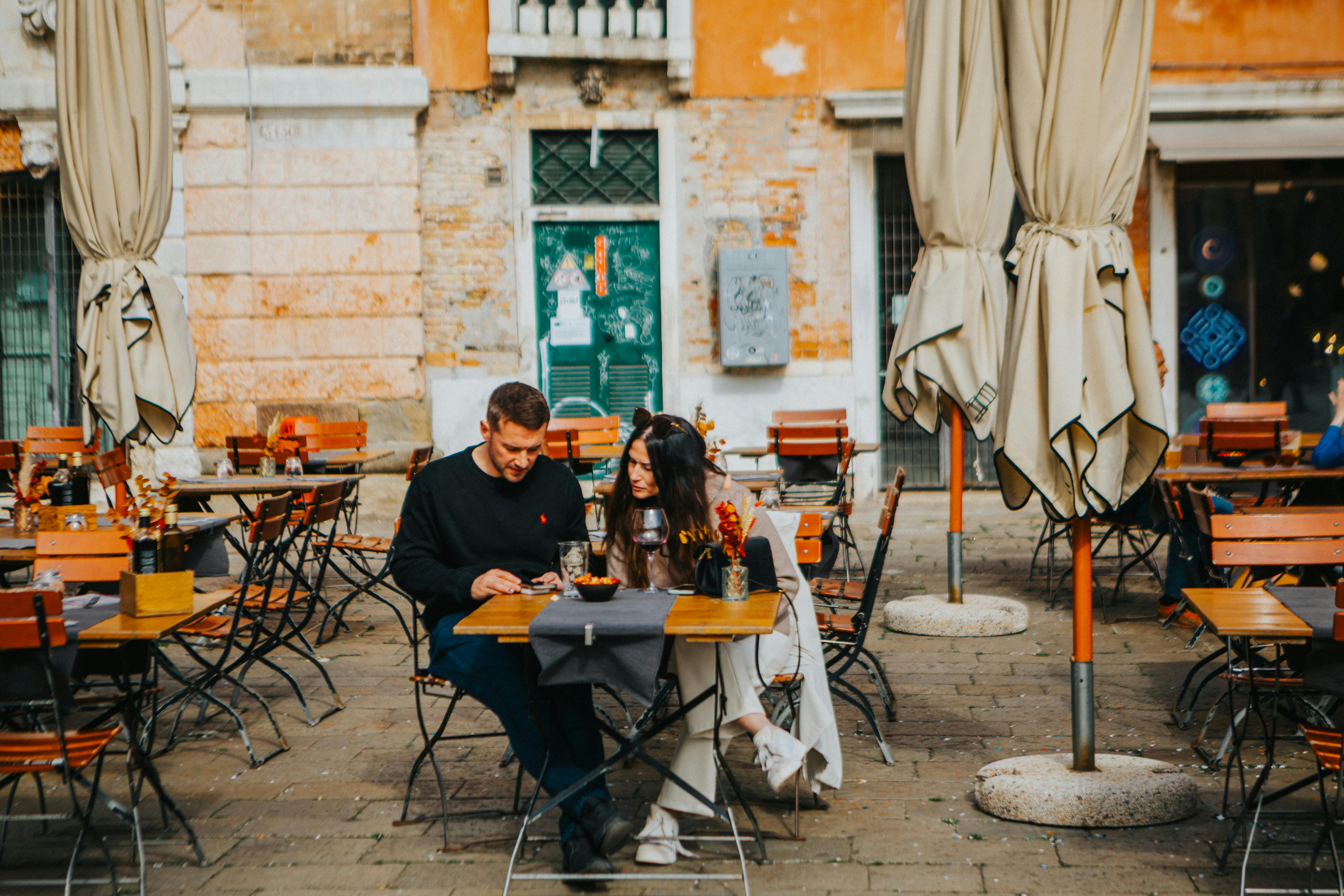 American tourists speaking loudly at an outdoor European café while locals converse quietly