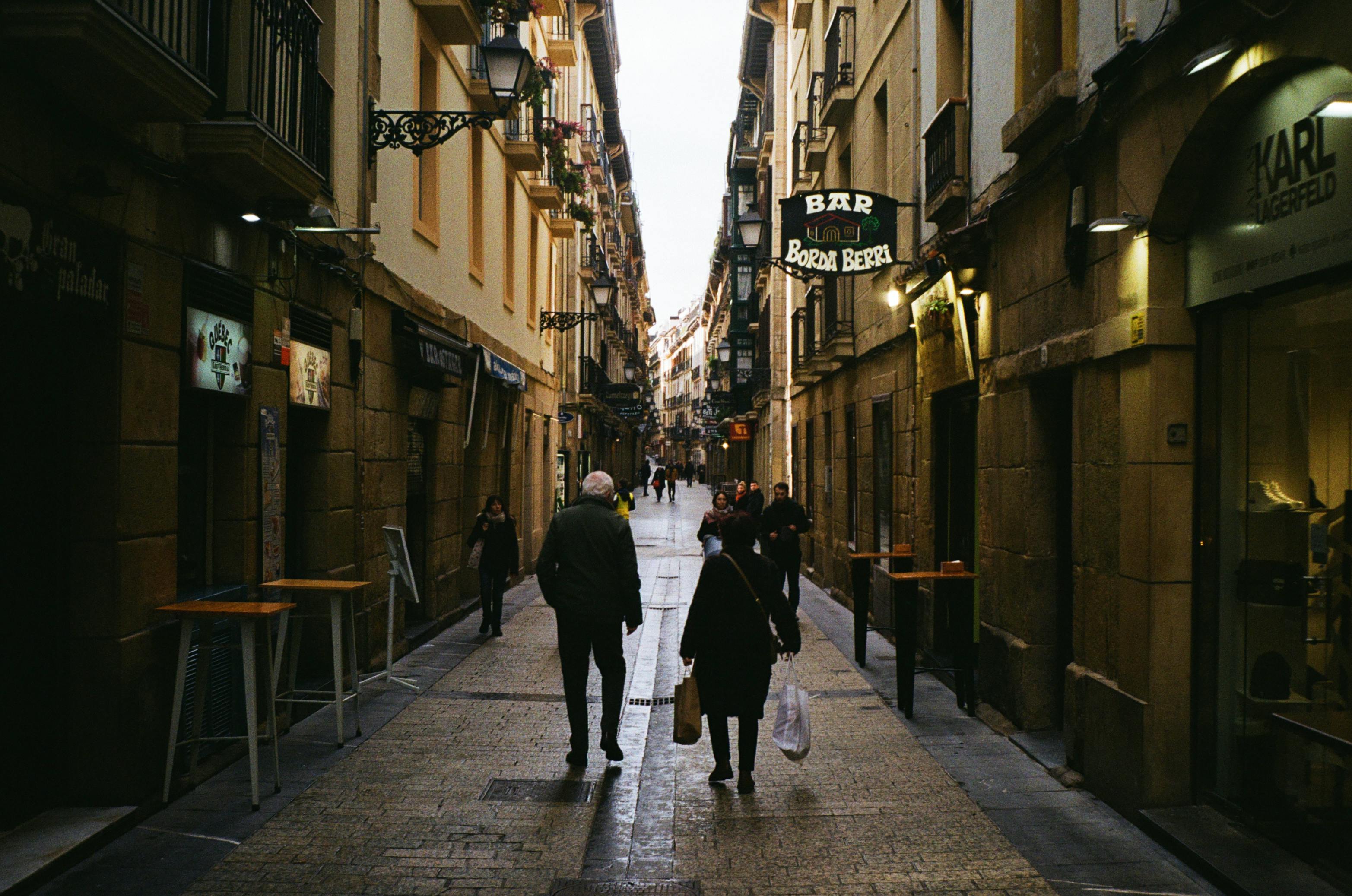 Tourists walking quickly through a narrow European street while locals stroll at a slower pace